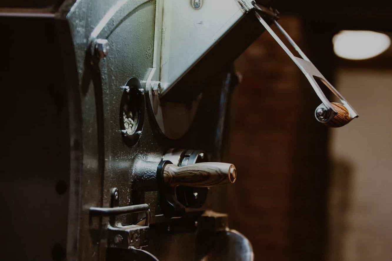 Frisch geröstete Kaffeebohnen im Röstprozess in der Maschine bei Kaffeesack – Handwerkskunst für besten Spezialitätenkaffee